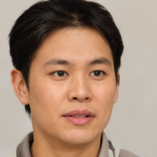 Joyful asian young-adult male with short  brown hair and brown eyes