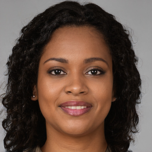 Joyful black young-adult female with long  brown hair and brown eyes