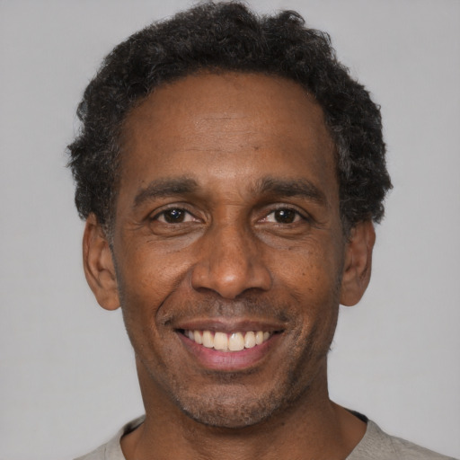 Joyful black adult male with short  black hair and brown eyes