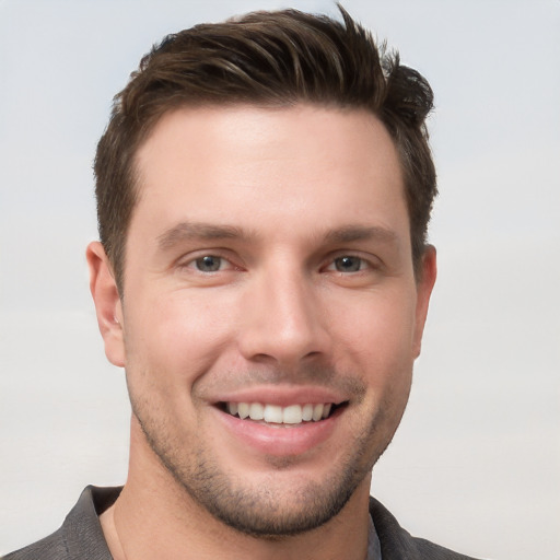 Joyful white young-adult male with short  brown hair and grey eyes