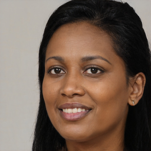 Joyful black young-adult female with long  black hair and brown eyes
