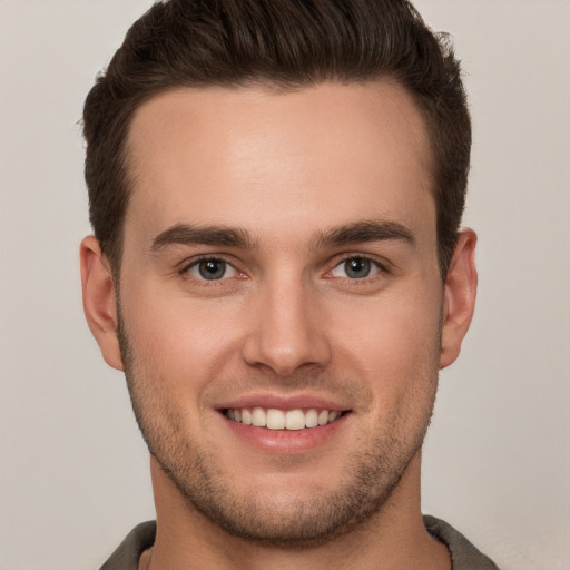 Joyful white young-adult male with short  brown hair and grey eyes