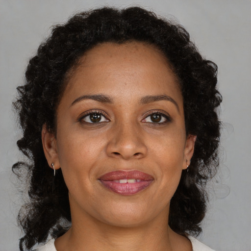 Joyful black adult female with long  brown hair and brown eyes