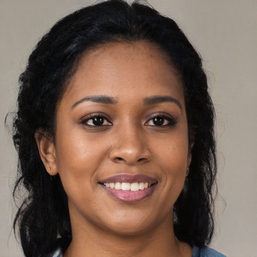 Joyful black young-adult female with long  brown hair and brown eyes