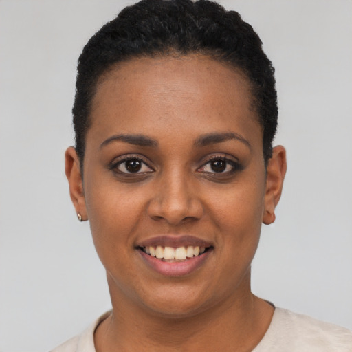 Joyful black young-adult female with short  black hair and brown eyes