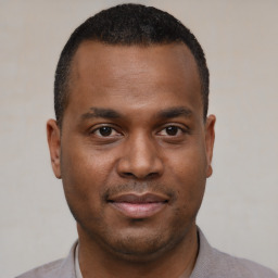 Joyful black young-adult male with short  black hair and brown eyes