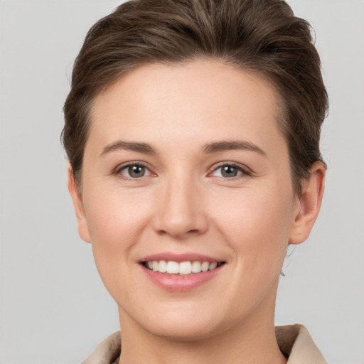 Joyful white young-adult female with short  brown hair and grey eyes