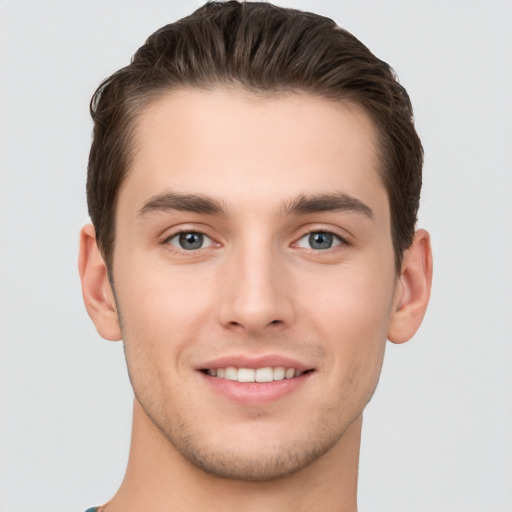 Joyful white young-adult male with short  brown hair and grey eyes