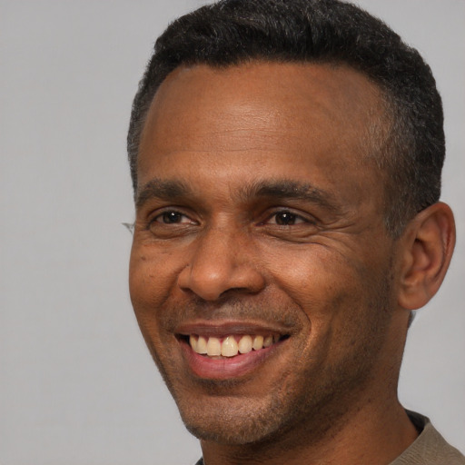 Joyful black adult male with short  brown hair and brown eyes
