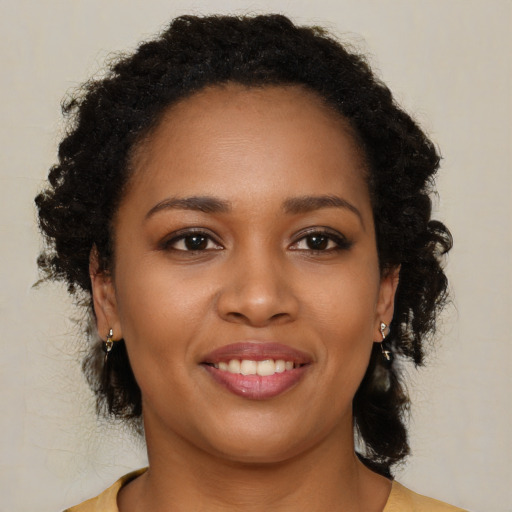 Joyful black young-adult female with long  brown hair and brown eyes