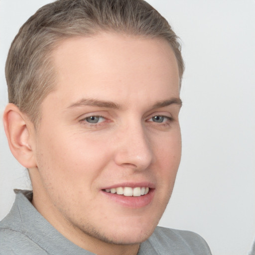 Joyful white young-adult male with short  brown hair and grey eyes