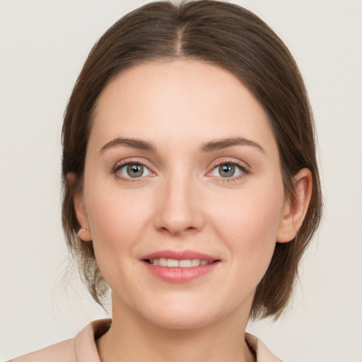 Joyful white young-adult female with medium  brown hair and grey eyes