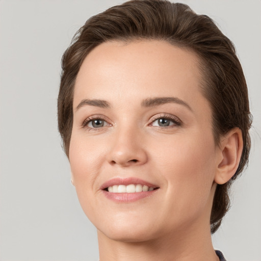 Joyful white young-adult female with medium  brown hair and grey eyes