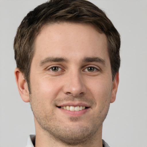 Joyful white young-adult male with short  brown hair and grey eyes