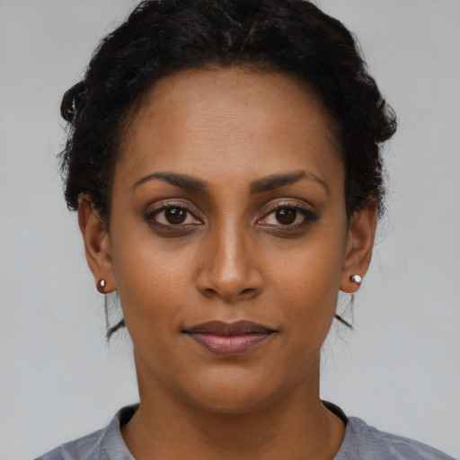 Joyful black young-adult female with short  black hair and brown eyes