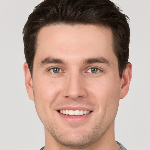 Joyful white young-adult male with short  brown hair and grey eyes