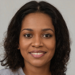 Joyful black young-adult female with long  brown hair and brown eyes