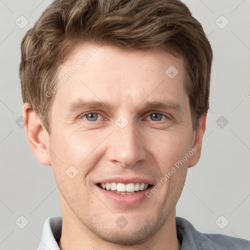 Joyful white young-adult male with short  brown hair and grey eyes