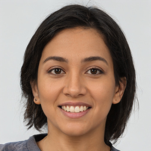 Joyful latino young-adult female with medium  brown hair and brown eyes