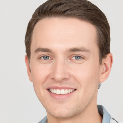 Joyful white young-adult male with short  brown hair and grey eyes