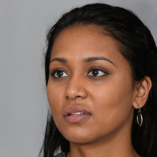 Joyful black young-adult female with long  black hair and brown eyes