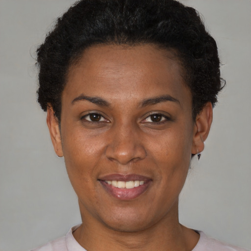 Joyful black young-adult female with short  brown hair and brown eyes