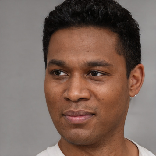 Joyful black young-adult male with short  black hair and brown eyes