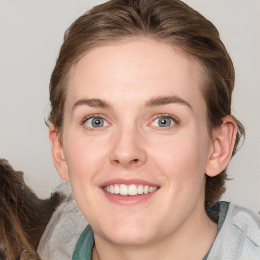 Joyful white young-adult female with medium  brown hair and blue eyes