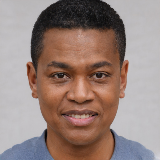 Joyful black young-adult male with short  brown hair and brown eyes