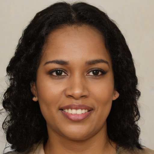 Joyful black young-adult female with long  brown hair and brown eyes