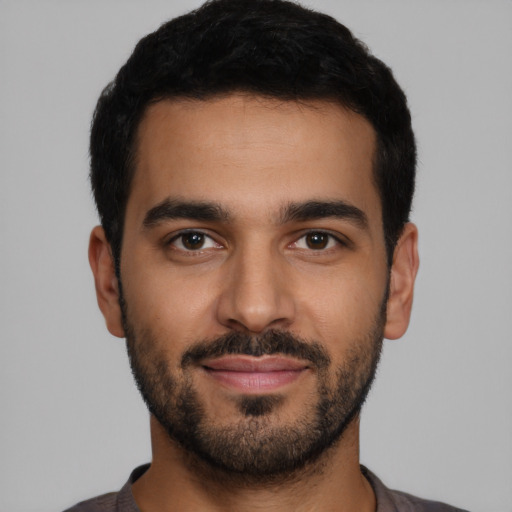 Joyful latino young-adult male with short  black hair and brown eyes