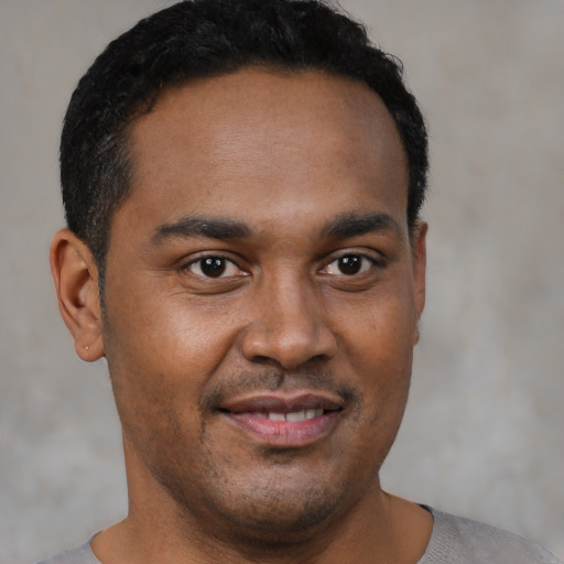 Joyful black young-adult male with short  brown hair and brown eyes