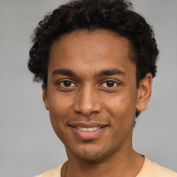 Joyful black young-adult male with short  brown hair and brown eyes