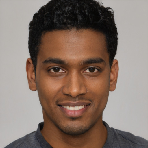 Joyful black young-adult male with short  black hair and brown eyes