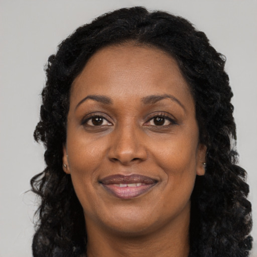 Joyful black adult female with long  black hair and brown eyes
