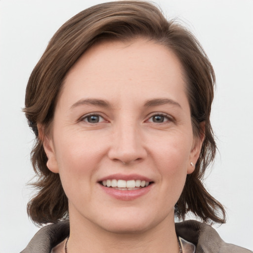 Joyful white young-adult female with medium  brown hair and grey eyes