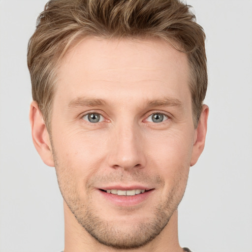 Joyful white young-adult male with short  brown hair and grey eyes