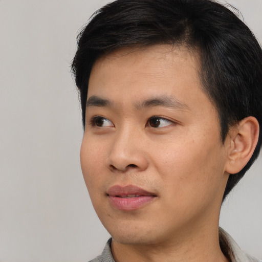 Joyful asian young-adult male with short  black hair and brown eyes