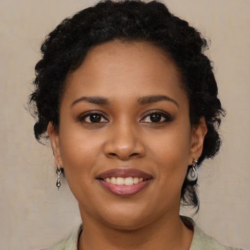 Joyful black young-adult female with long  brown hair and brown eyes