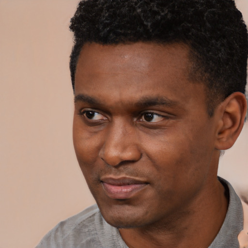 Joyful black young-adult male with short  black hair and brown eyes
