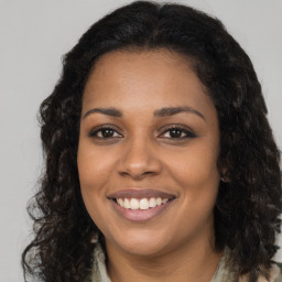 Joyful black young-adult female with long  brown hair and brown eyes