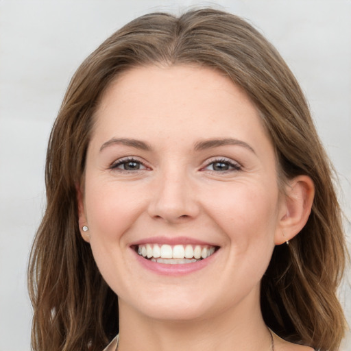 Joyful white young-adult female with medium  brown hair and grey eyes