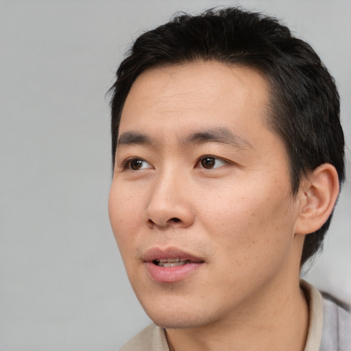 Joyful asian young-adult male with short  black hair and brown eyes