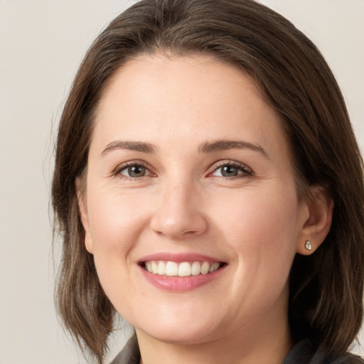 Joyful white young-adult female with medium  brown hair and grey eyes