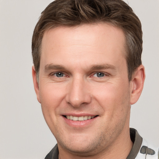 Joyful white young-adult male with short  brown hair and grey eyes