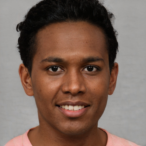 Joyful black young-adult male with short  brown hair and brown eyes