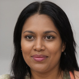 Joyful black young-adult female with long  brown hair and brown eyes