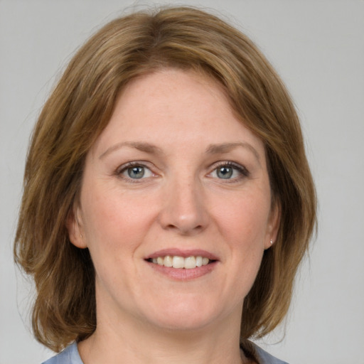 Joyful white adult female with medium  brown hair and blue eyes