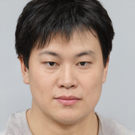 Joyful asian young-adult male with short  brown hair and brown eyes