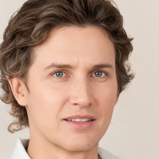 Joyful white young-adult male with medium  brown hair and grey eyes